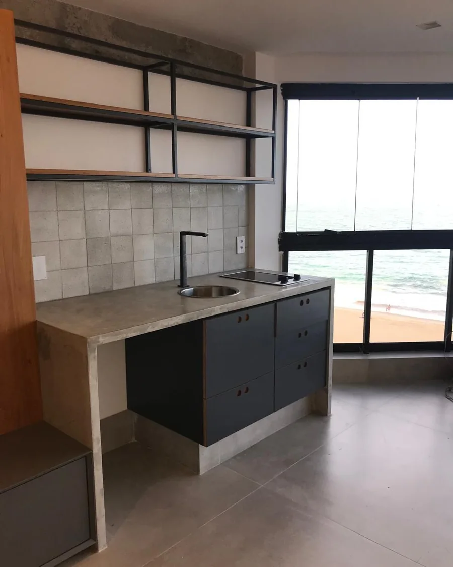 Cozinha reformada com prateleira metálica, marcenaria sob medida e bancada em cimento